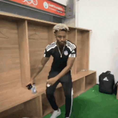 a man is dancing in a locker room with a sign that says santander on it