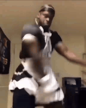 A Man Is Dancing In A Maid Costume In A Room . GIF