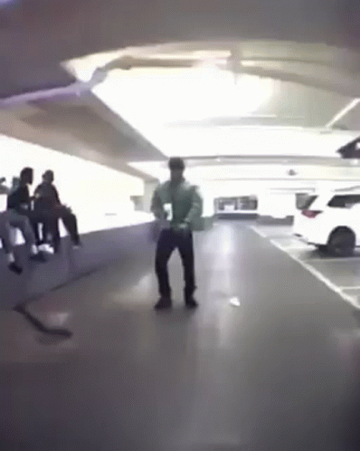 A Man Is Dancing In A Parking Garage With A Group Of People . GIF
