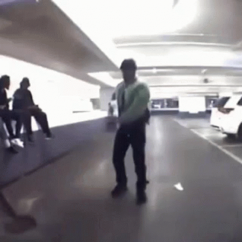 A Man Is Dancing In A Parking Garage With People Sitting On The Floor . GIF
