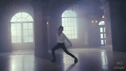 A Man Is Dancing In A Room With A Skz Player Logo GIF