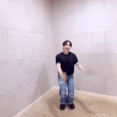 A Man Is Dancing In A Room With A White Wall . GIF