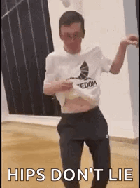 A Man Is Dancing In A Room With The Words `` Hips Do N't Lie '' Written On The Bottom . GIF