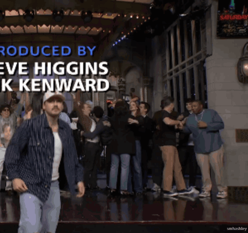 A Man Is Dancing In Front Of A Crowd With The Words Produced By Eve Higgins K Kenward GIF
