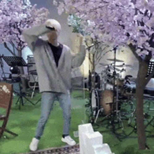 A Man Is Dancing In Front Of A Drum Set And A Cherry Blossom Tree GIF
