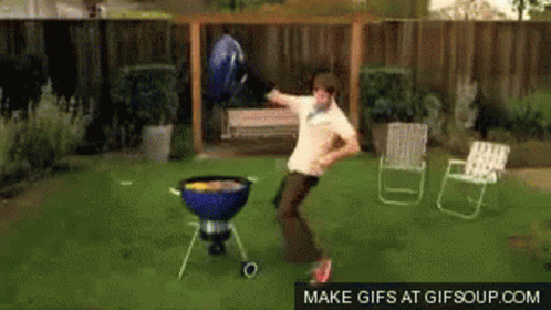 A Man Is Dancing In Front Of A Grill In A Backyard GIF
