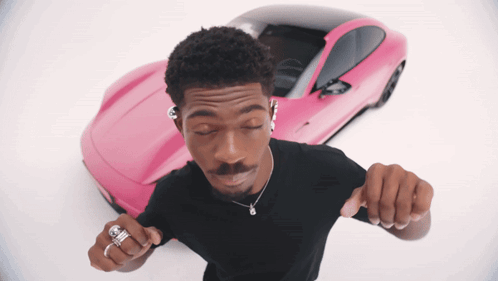 A Man Is Dancing In Front Of A Pink Sports Car GIF