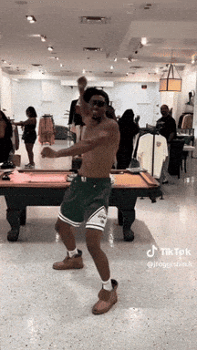 A Man Is Dancing In Front Of A Pool Table In A Store . GIF
