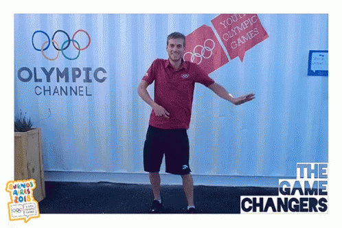 A Man Is Dancing In Front Of A Sign For The Olympic Channel GIF