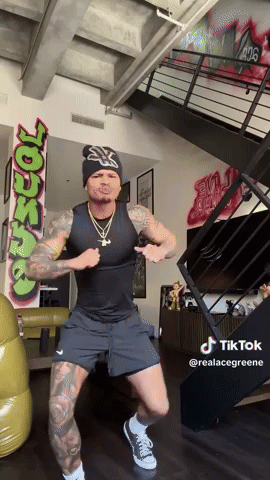 A Man Is Dancing In Front Of A Wall With Graffiti That Says ' Ross ' GIF