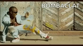 A Man Is Dancing In Front Of A Wooden Door With The Word Bombaclat Written On The Bottom . GIF