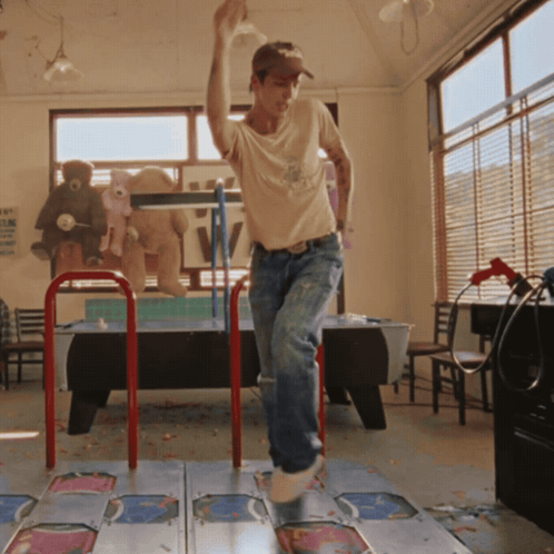 a man is dancing on a dance mat in a room with a sign on the wall that says tv