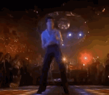 A Man Is Dancing On A Disco Floor In Front Of A Crowd . GIF