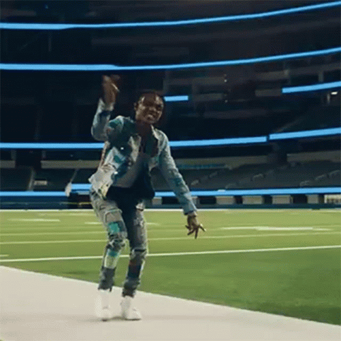 A Man Is Dancing On A Football Field . GIF