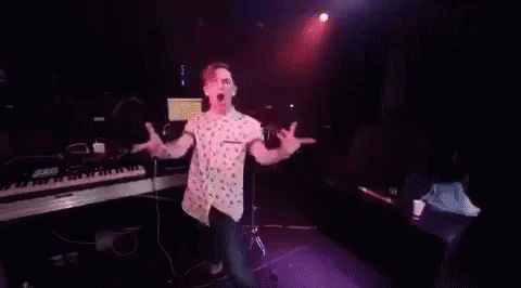 A Man Is Dancing On A Stage In Front Of A Crowd In A Club . GIF