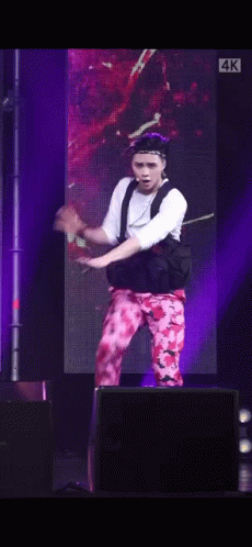 A Man Is Dancing On A Stage In Front Of A Large Screen . GIF