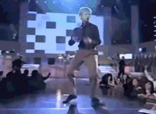 a man is dancing on a stage with a crowd watching