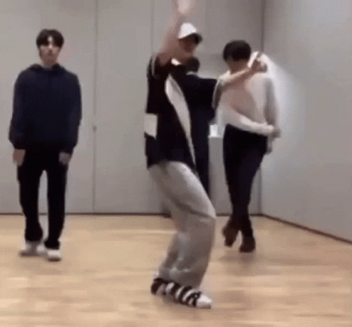A Man Is Dancing On A Wooden Floor In A Room While Two Other Men Watch . GIF