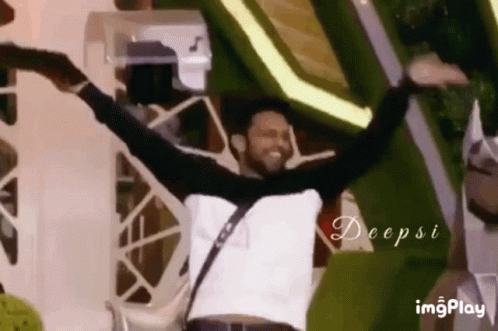 A Man Is Dancing With His Arms Outstretched In Front Of A Crowd . GIF