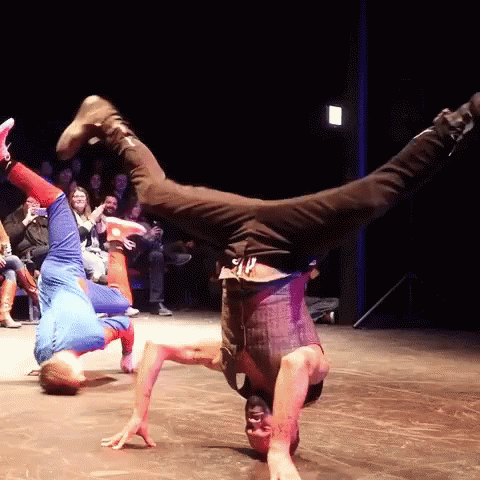 A Man Is Doing A Handstand In Front Of A Crowd Of People GIF