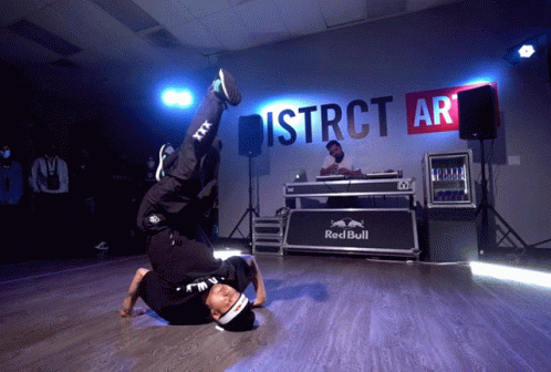 A Man Is Doing A Handstand In Front Of A Sign That Says District Ar GIF
