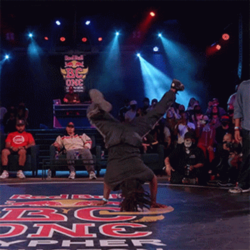 A Man Is Doing A Handstand In Front Of A Sign That Says Red Bull On It GIF
