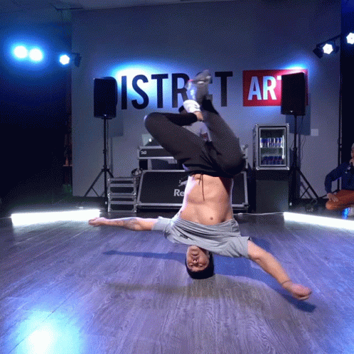 A Man Is Doing A Handstand In Front Of A Wall That Says District Art GIF
