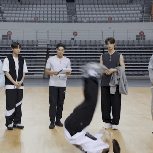 A Man Is Doing A Handstand On A Basketball Court In Front Of Empty Seats GIF
