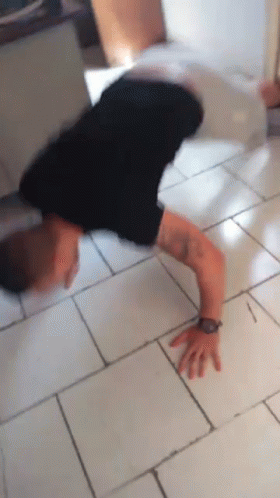 A Man Is Doing A Handstand On A Tile Floor GIF
