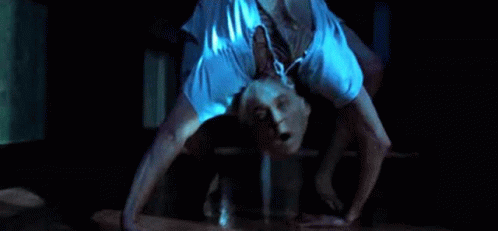 a man is doing a handstand on the floor in a dark room with his mouth open .