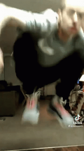 A Man Is Doing A Trick In Front Of A Mirror While Wearing Nike Shoes . GIF