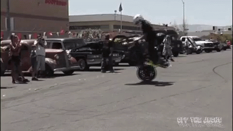A Man Is Doing A Trick On A Motorcycle In Front Of A Crowd Of People . GIF