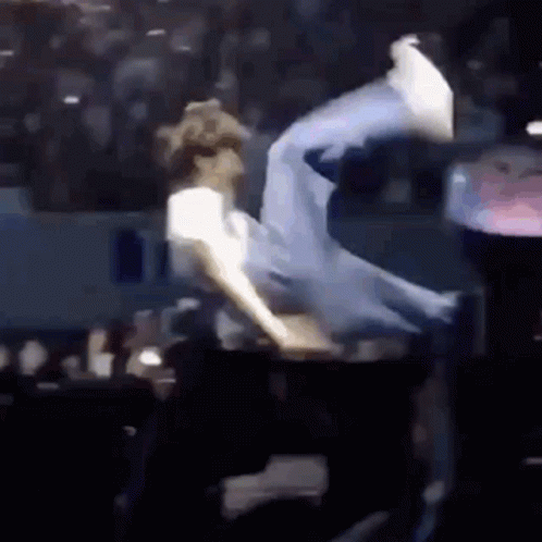 A Man Is Doing A Trick On A Stage In Front Of A Crowd Of People . GIF