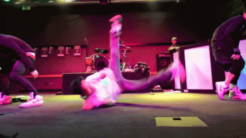 A Man Is Doing A Trick On A Stage With A Drum Set In The Background GIF