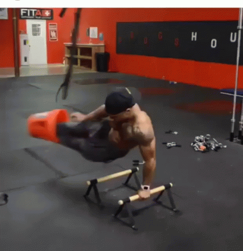 A Man Is Doing Exercises In A Gym With A Sign That Says Fit GIF