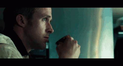 A Man Is Drinking A Cup Of Coffee And Looking Out The Window GIF