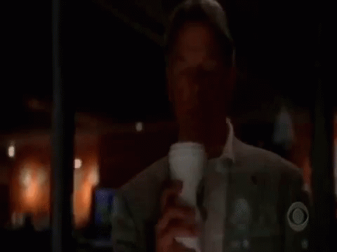 A Man Is Drinking A Cup Of Coffee From A Cup In A Dark Room . GIF
