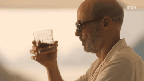 a man is drinking a glass of whiskey with a max logo behind him
