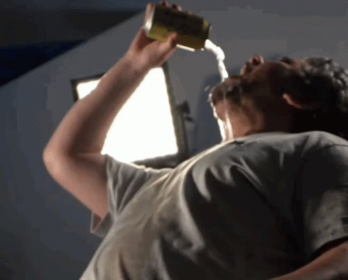 A Man Is Drinking From A Can With Water Pouring Out Of It Into His Mouth GIF