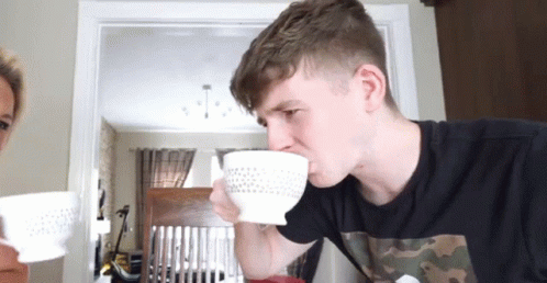 A Man Is Drinking From A White Bowl With A Polka Dot Pattern GIF