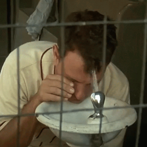 Man Drinking Water From Fountain In Cage GIF