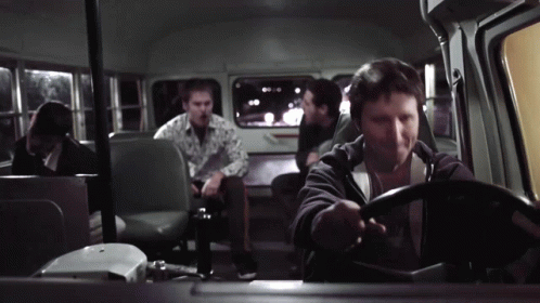 A Man Is Driving A Bus With Other People Sitting In The Back Seats GIF