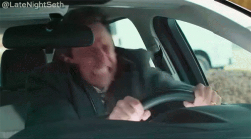 A Man Is Driving A Car And Making A Face . GIF