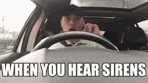 A Man Is Driving A Car And Talking On A Cell Phone While Wearing A Hat . GIF