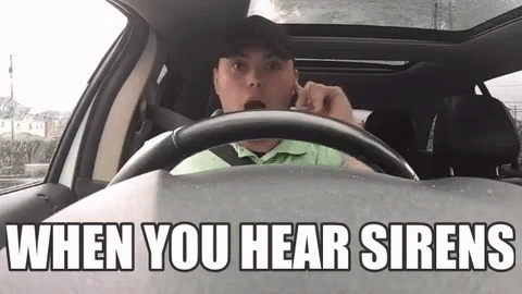 A Man Is Driving A Car And Talking On A Cell Phone With The Words `` When You Hear Sirens '' Above Him . GIF