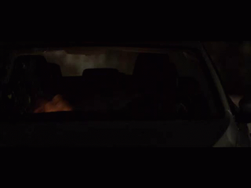 A Man Is Driving A Car At Night With His Head Out The Window GIF