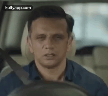 A Man Is Driving A Car With His Eyes Closed And His Mouth Open . GIF