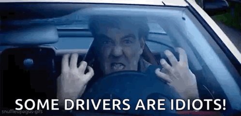 A Man Is Driving A Car With His Hands On The Steering Wheel And The Words `` Some Drivers Are Idiots '' Below Him . GIF