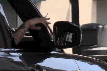 A Man Is Driving A Car With His Hands Out The Window . GIF