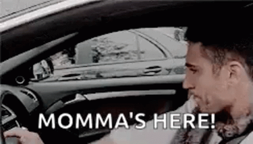 A Man Is Driving A Car With The Words `` Momma 'S Here '' Written On It . GIF